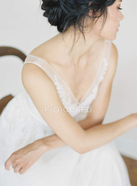Женщина в свадебном платье сидит на стуле — стоковое фото