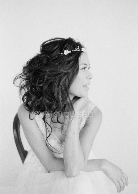 Жінка в весільній сукні сидить на стільці — стокове фото