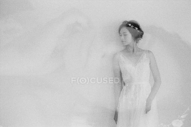 Mulher em vestido de noiva por parede — Fotografia de Stock