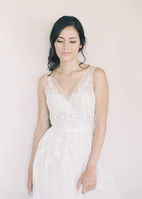 Femme en robe de mariée debout par le mur — Photo de stock