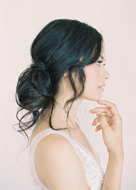 Femme en robe de mariée avec la main au menton — Photo de stock