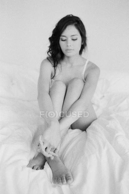 Женщина в изысканном белье сидит на кровати — стоковое фото