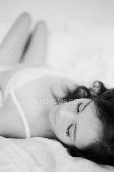 Mujer en ropa interior exquisita acostada en la cama - foto de stock