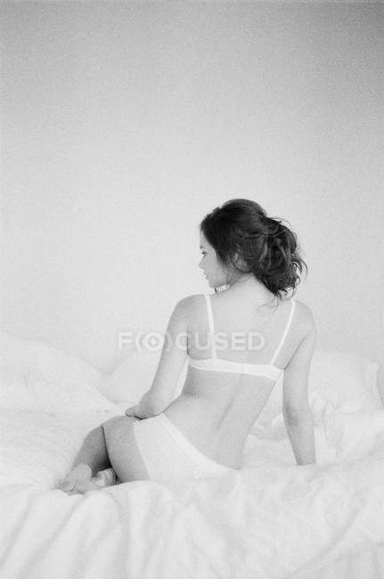 Donna in lingerie squisita seduta sul letto — Foto stock