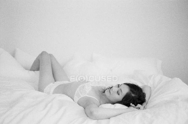 Frau in exquisiter Dessous auf Bett liegend — Stockfoto