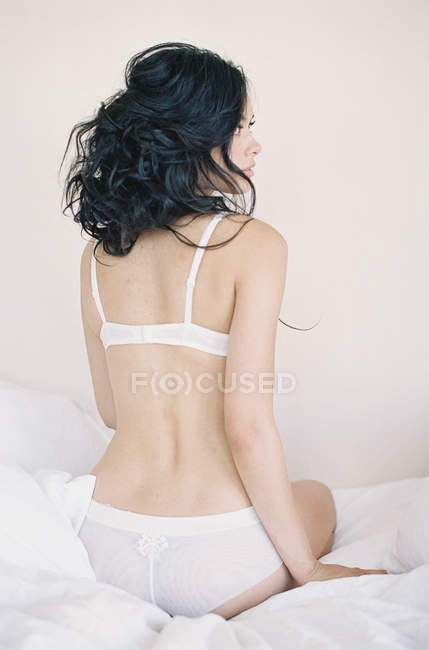Frau in exquisiter Dessous sitzt auf dem Bett — Stockfoto