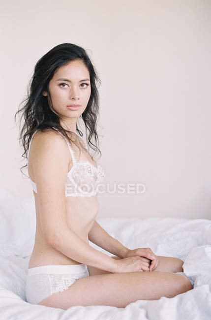 Femme en lingerie exquise assise sur le lit — Photo de stock