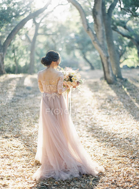 Frau im Brautkleid steht im Wald — Stockfoto