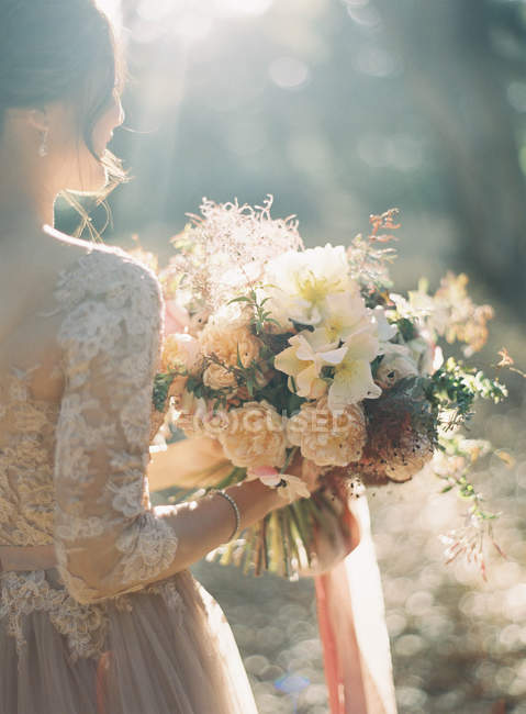 Noiva com buquê de flores na floresta — Fotografia de Stock