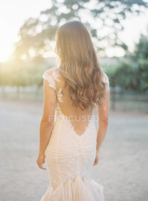 Rear view of brunette woman in white dress at nature — Stock Photo