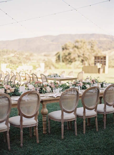 Mesas de casamento com flores e fileiras de cadeiras — Fotografia de Stock