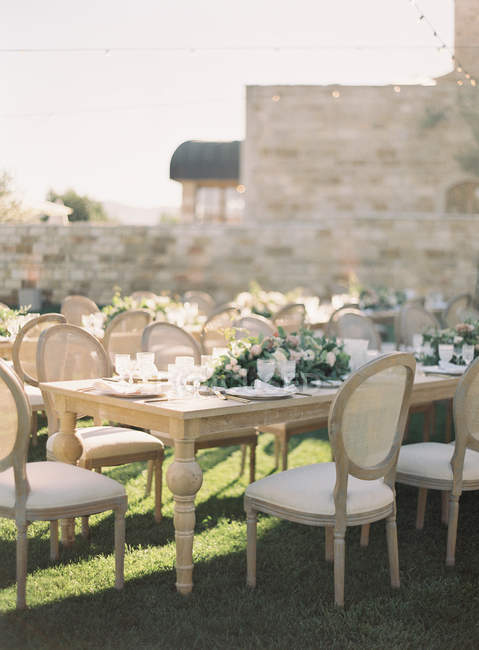 Свадебные столы с цветами и рядами стульев — стоковое фото