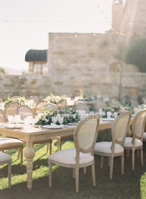 Tables de mariage avec des fleurs et des rangées de chaises — Photo de stock