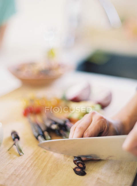 Женщина режет черную морковь — стоковое фото