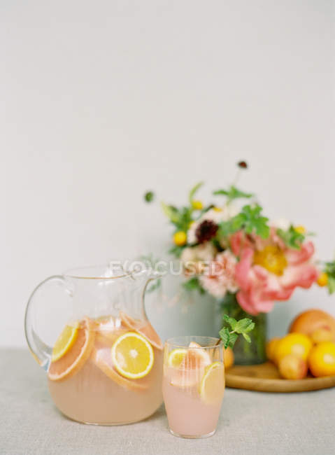 Fresh beverage with oranges and bouquet — Stock Photo
