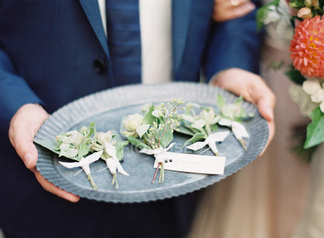 Man holding fresh floral boutonnieres — Stock Photo