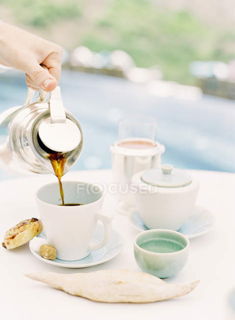 Mano femenina vertiendo café en taza - foto de stock