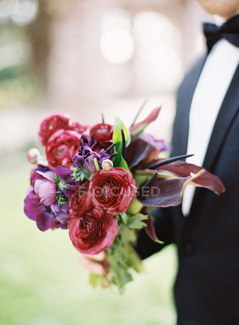 Groom holding wedding bouquet — Stock Photo