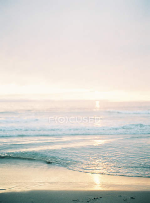 Playa con puesta de sol en el fondo - foto de stock