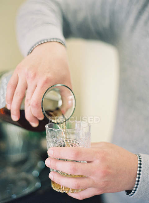 Hombre vertiendo bebida en el vaso - foto de stock