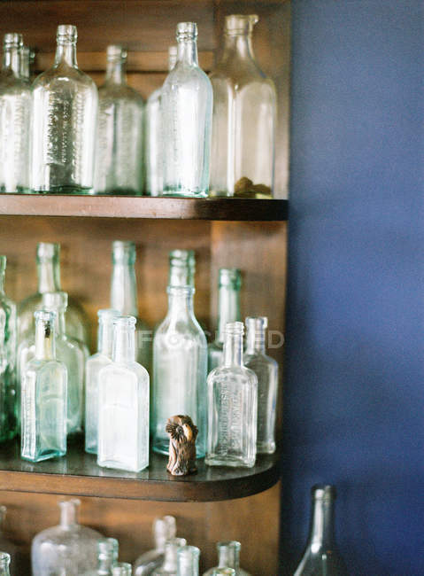 Glass bottles on wooden shelves — Stock Photo