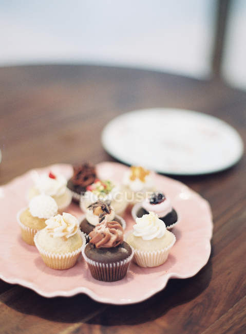 Cupcakes de colores en bandeja rosa - foto de stock
