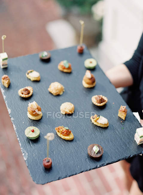 Woman holding wooden board with starters — Stock Photo