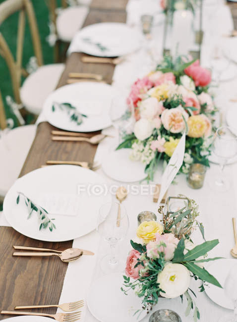 Floral arrangement on setting table — Stock Photo