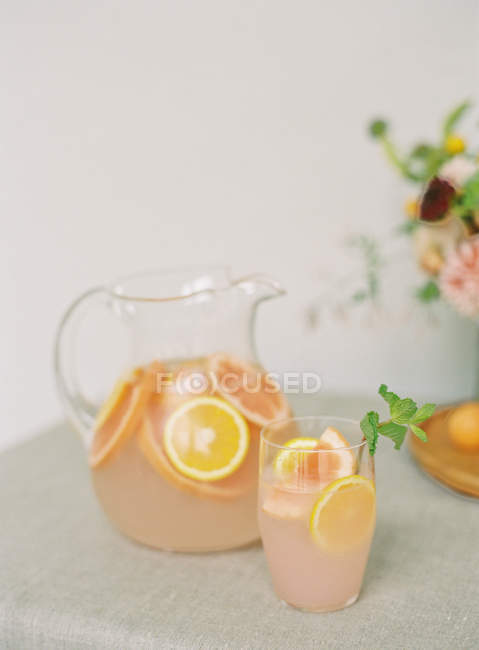 Баночка зі свіжим цитрусовим напоєм на столі — стокове фото