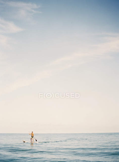 Paysage marin avec personne crânant sur la planche de surf le jour ensoleillé — Photo de stock