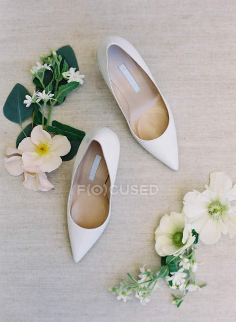 Chaussures et fleurs blanches à talons hauts — Photo de stock