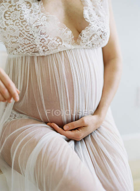 Mujer embarazada cogida de la mano a la barriga - foto de stock