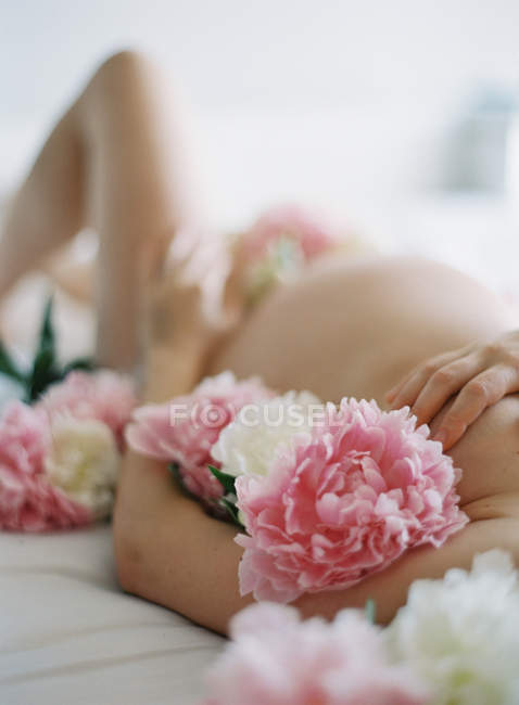 Pregnant woman body covered with peonies — Stock Photo