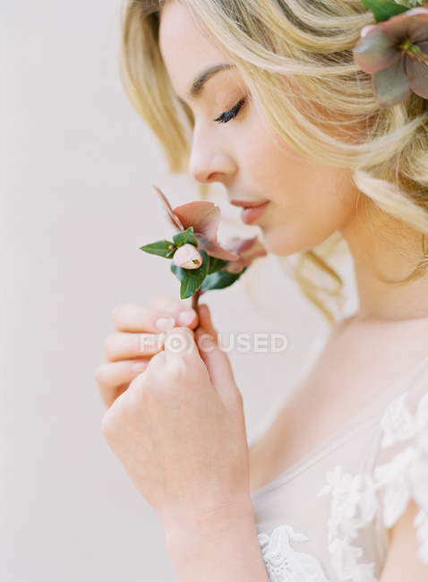 Женщина в свадебном платье пахнущий цветок — стоковое фото