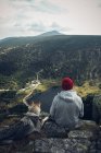 Young man with dog sitting on cliff edge — Stock Photo