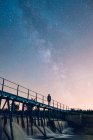 Homem de pé na ponte e olhando para as estrelas — Fotografia de Stock