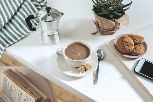 Кава з печивом і горшковою рослиною на стільниці — стокове фото