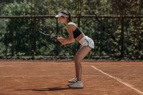 Jeune femme debout sur le court de tennis en attente de servir — Photo de stock