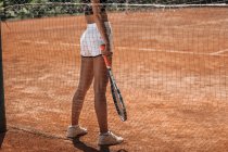 Schnappschuss von sportlicher Frau mit Tennisschläger steht auf Platz — Stockfoto