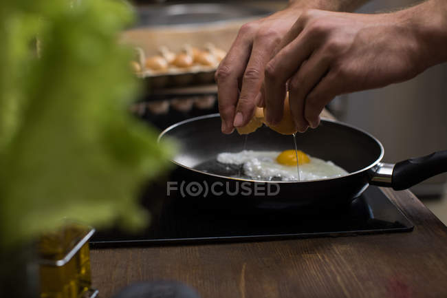 Joven preparando huevos - foto de stock