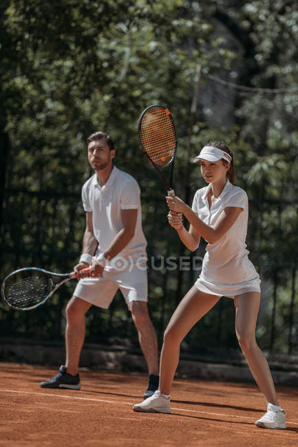 Jovem homem e mulher jogando tênis como equipe — Fotografia de Stock