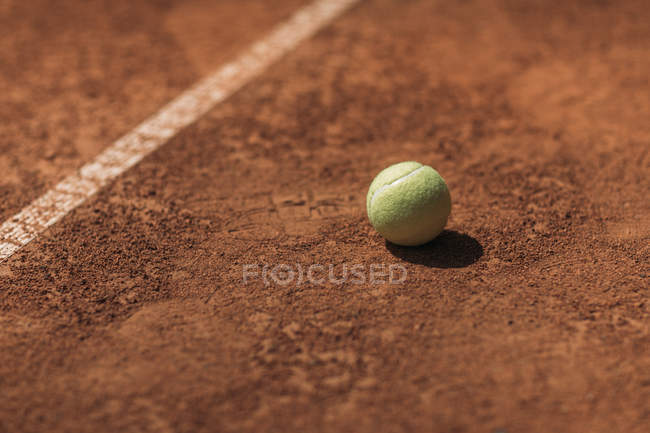 Bola de tênis deitado no campo sob luz solar brilhante — Fotografia de Stock