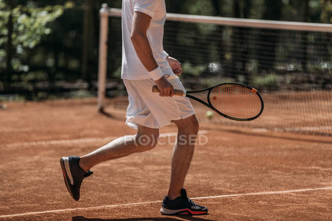 Обрезанный снимок мужчины в профессиональной спортивной одежде, играющего в теннис — стоковое фото