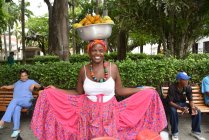 Frau trägt Schale mit Früchten auf dem Kopf — Stockfoto