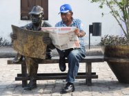 Hombre imitando estatua y leyendo periódico - foto de stock