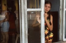Jeune femme debout près de la fenêtre — Photo de stock