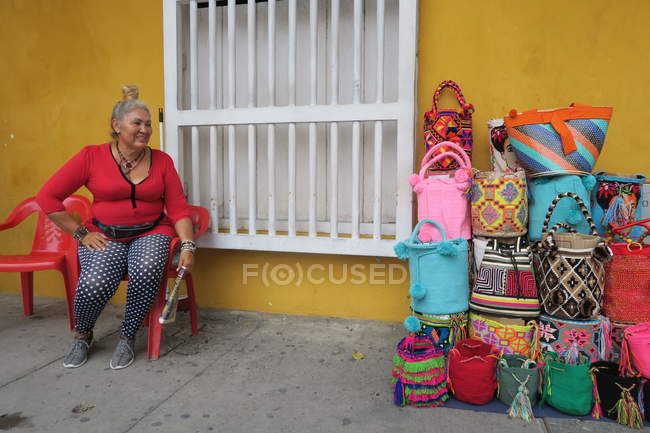 Señora sentada y vendiendo bolsos hechos a mano - foto de stock