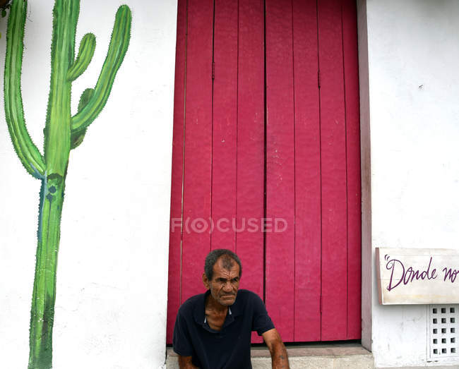 Uomo seduto a parete con cactus dipinto — Foto stock
