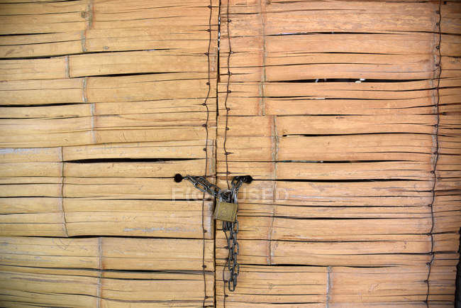 Bamboo door with padlock — Stock Photo