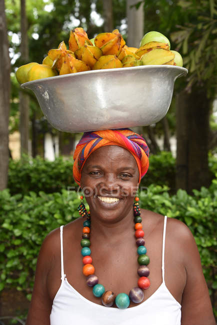 Женщина несет чашу с фруктами на голове — стоковое фото